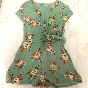 a green romper with yellow and orange floral designs